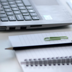 A notebook with a pencil, laptop, cup of coffee, and a ruler.